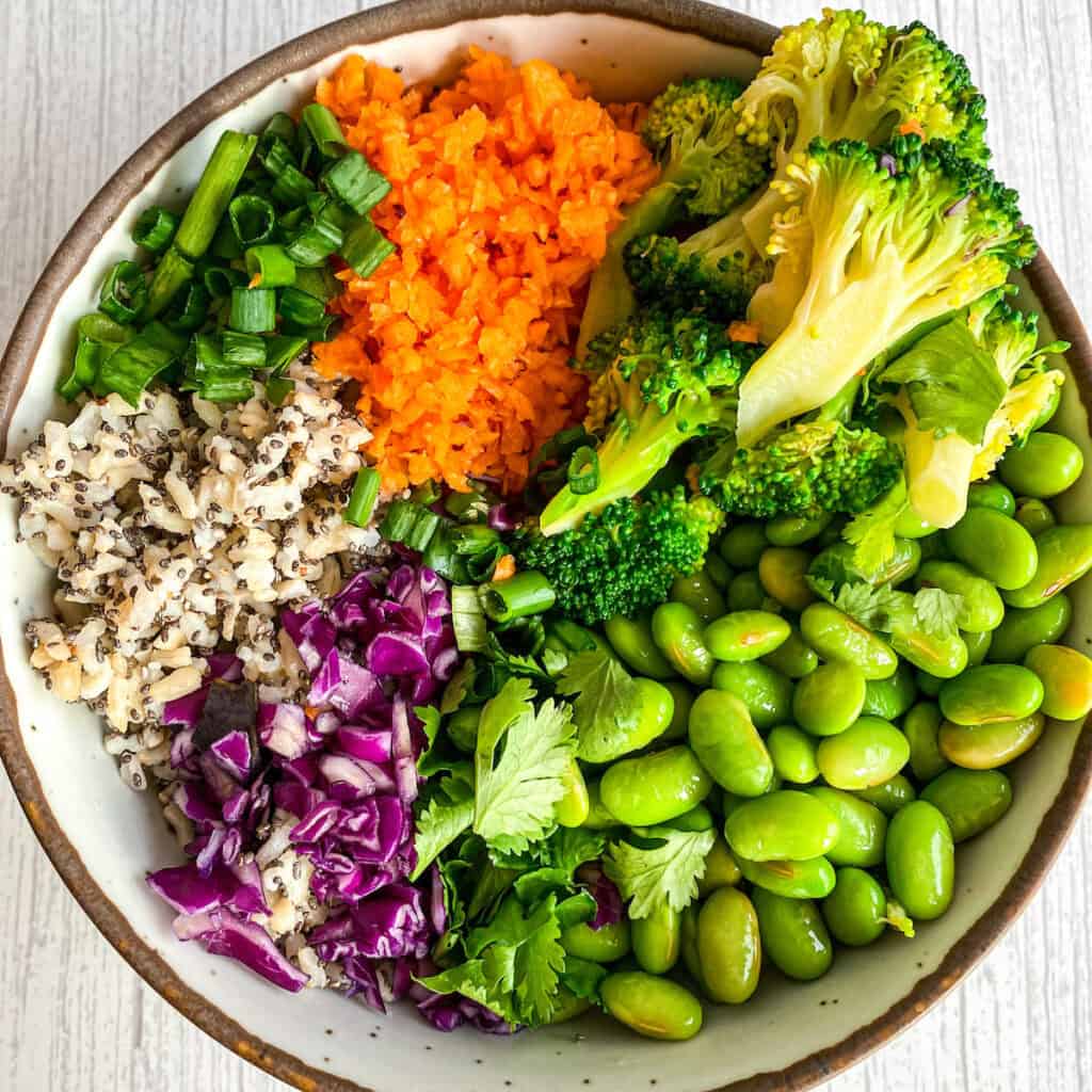 Vibrant plant-based edamame salad bowl with fresh coriander, spring onions, and toasted sesame seeds.