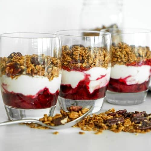 Healthy breakfast jars layered with homemade cinnamon granola, dairy-free coconut yogurt, and sliced baked plums with cinnamon.