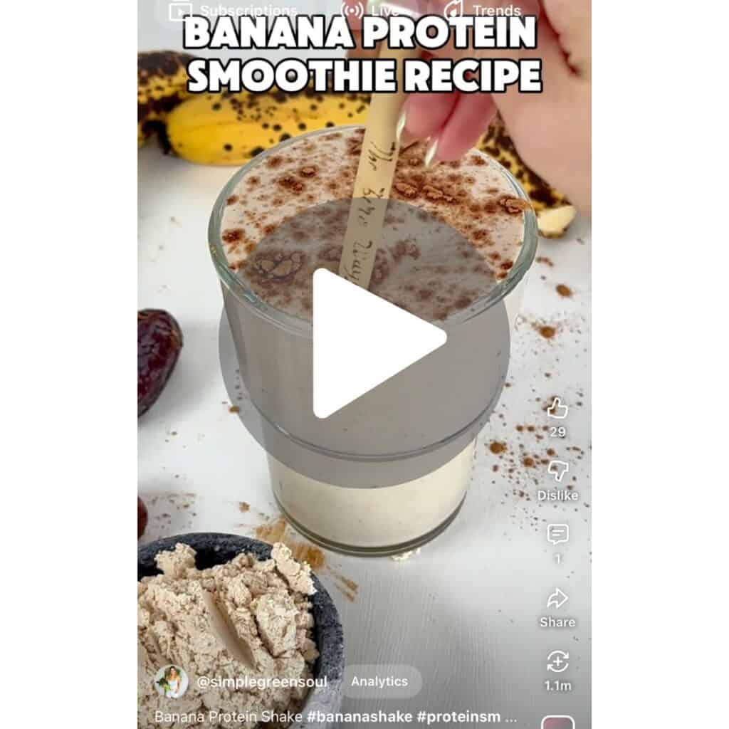 A screenshot showing a hand adding ingredients into a blender to make a banana protein smoothie, with a call to action to watch the full recipe on YouTube Shorts.