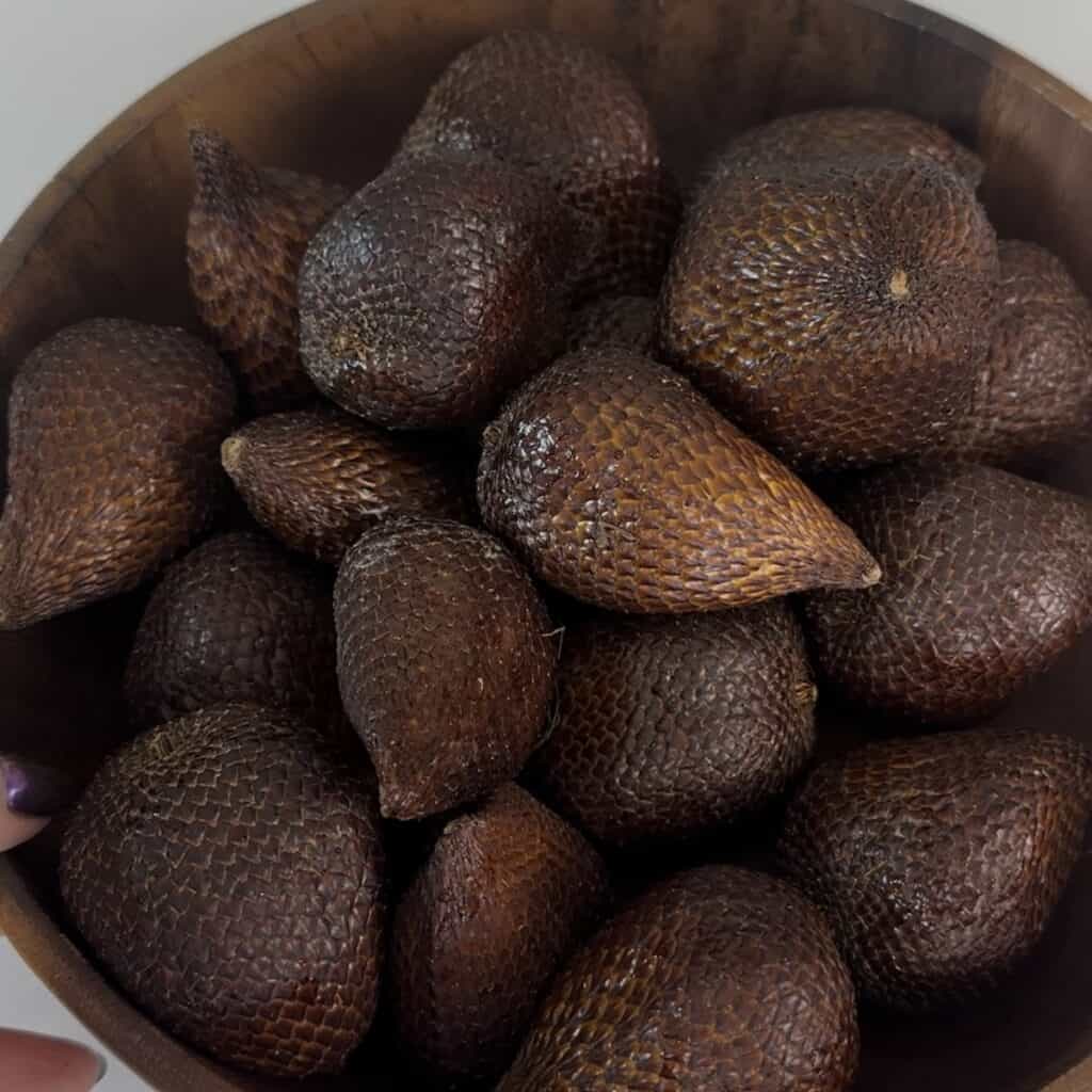 A large wooden bowl of salak fruit or snake fruit, taken from above, showing the brown scaly skin