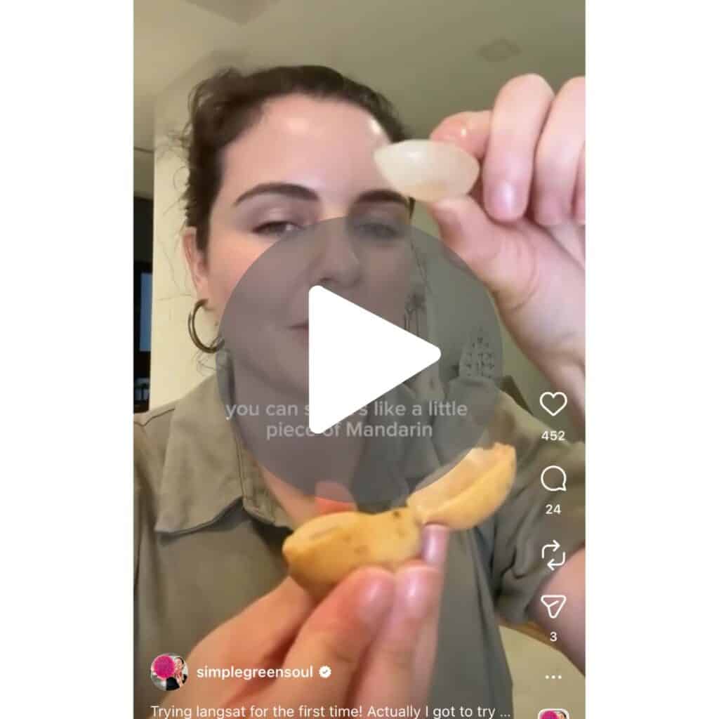 a screenshot of a video of a girl holding a longan fruit in her hands, peeled and ready to eat