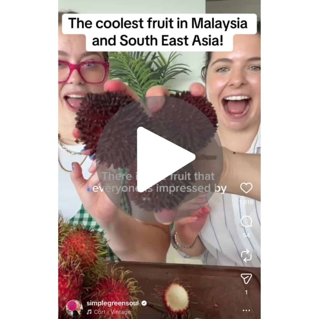 A screenshot of an instagram video of two girls holding the pulasan fruit, about to eat it. 