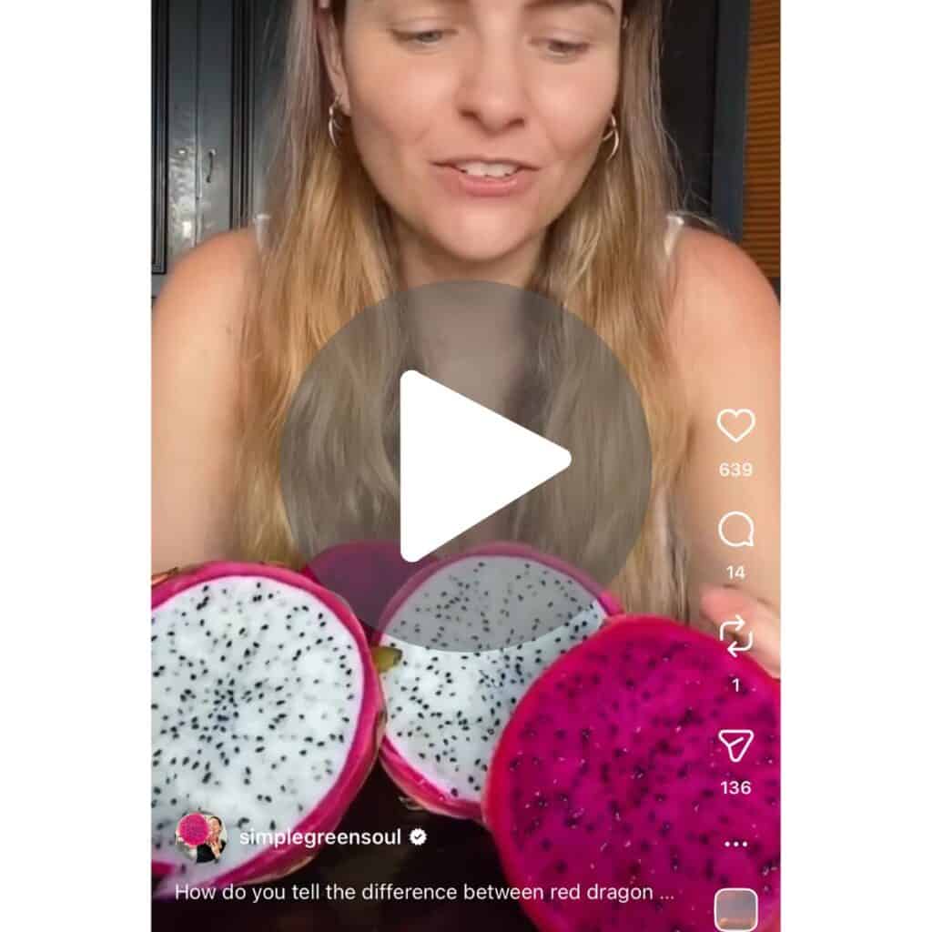 A screenshot of a video of a girl standing behind white and pink dragon fruit sliced in half, exposing the bright pink and white flesh with black seeds