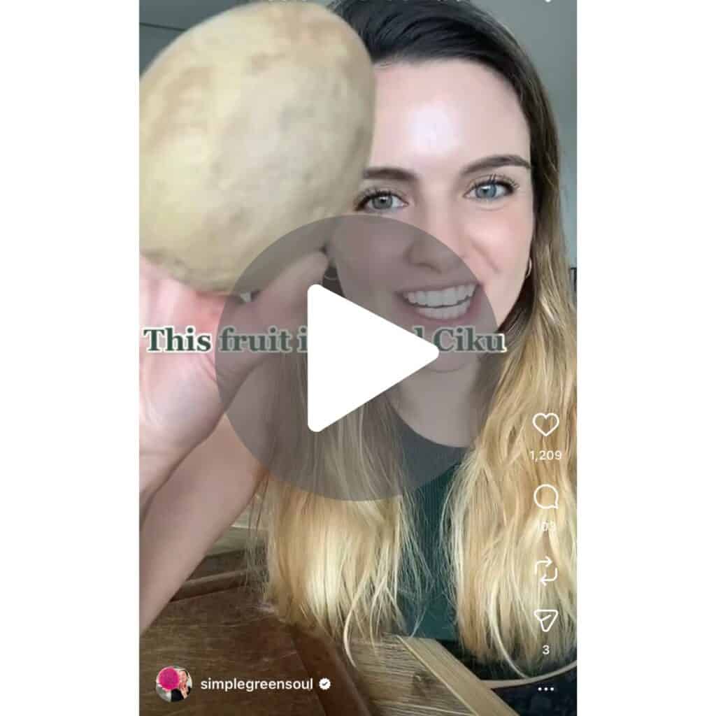 A screenshot of a video of an Australian girl living in Malaysia, holding a sapodilla fruit