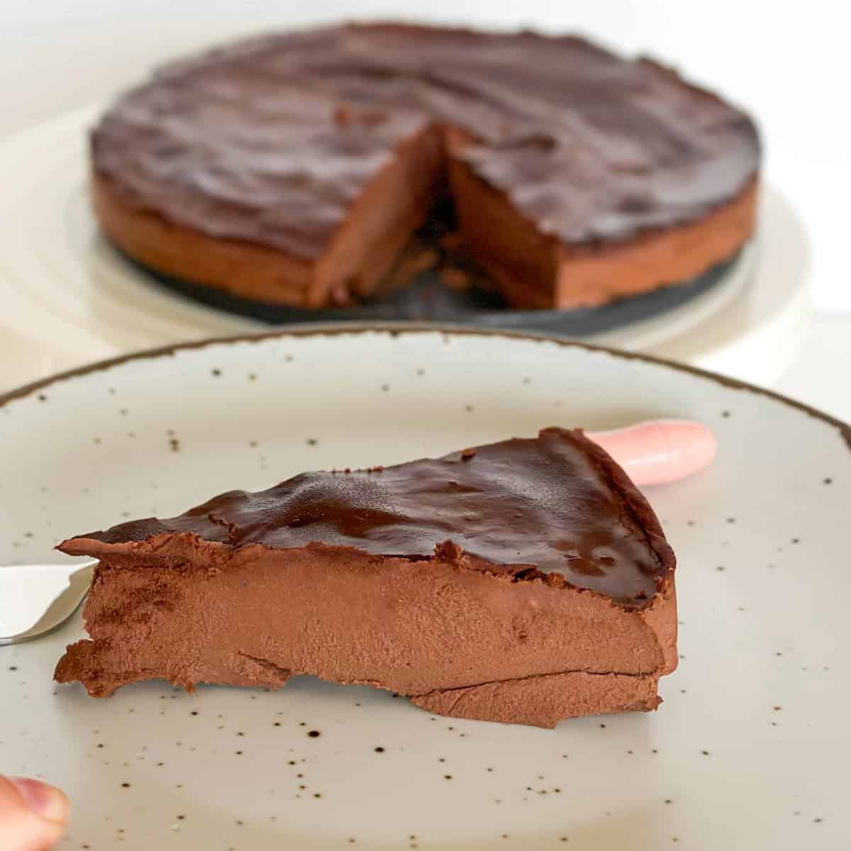 A close-up shot of a sliced 3-ingredient purple sweet potato chocolate cake on a white plate, highlighting its rich, dense, and fudgy texture.