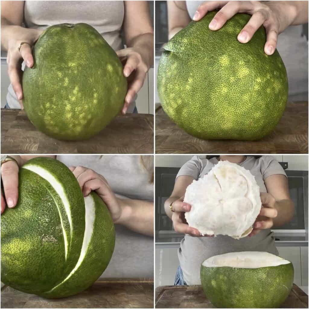 A close-up shot of a whole, large green pomelo being held on a wooden cutting board.