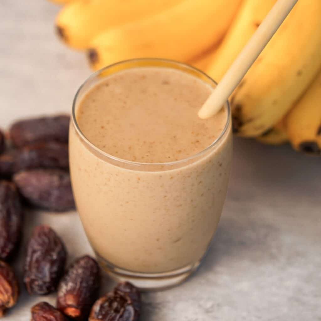 Date banana smoothie for pregnancy served in a glass with ripe bananas and Medjool dates for an easy date smoothie recipe.