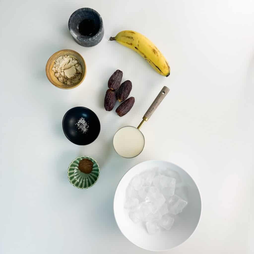 Ingredients for a date banana smoothie recipe including soy milk, banana, Medjool dates, cinnamon, vanilla, protein powder, salt, and ice.