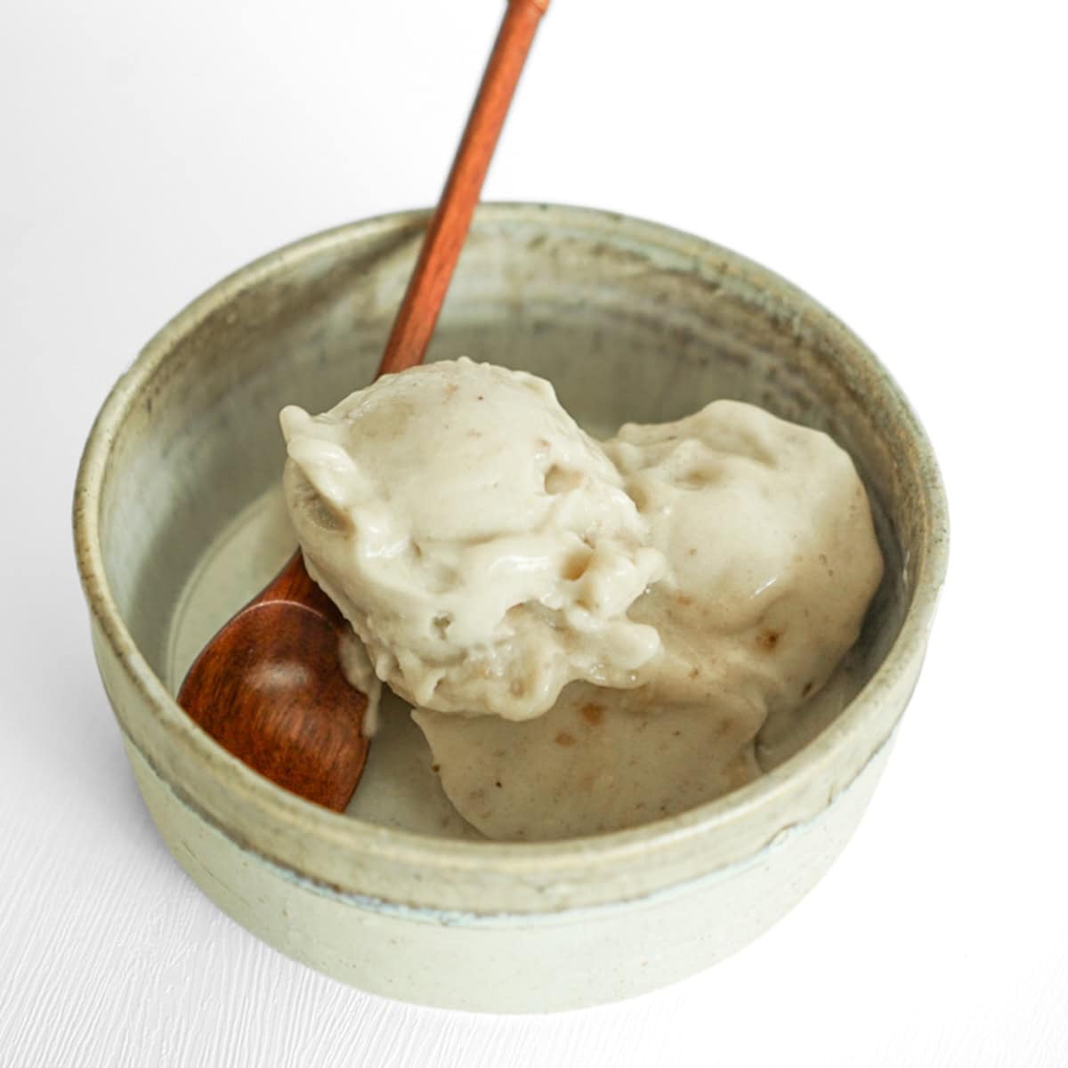 Creamy one-ingredient banana nice cream served in a bowl with a wooden spoon, made using this easy banana ice cream recipe in a food processor.