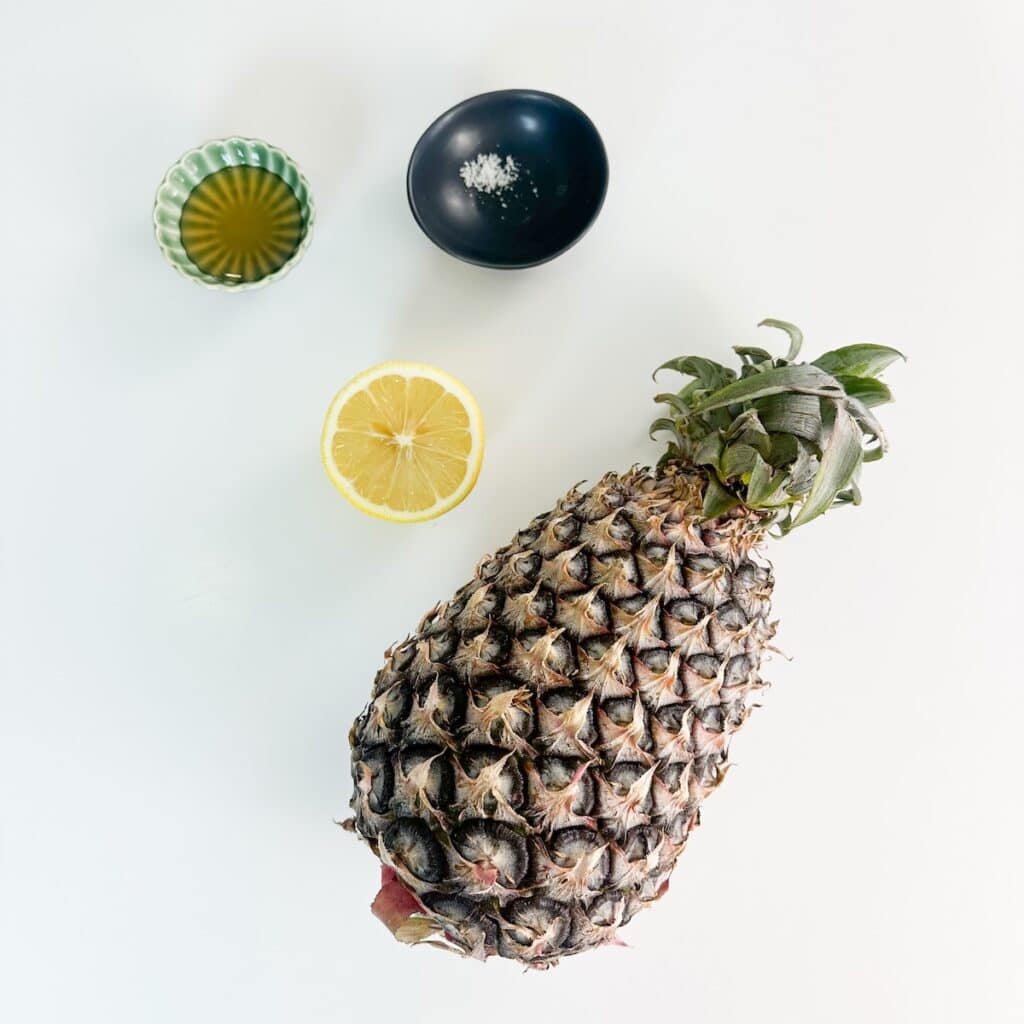 Ingredients for homemade pineapple juice including fresh pineapple, lemon, honey, and salt