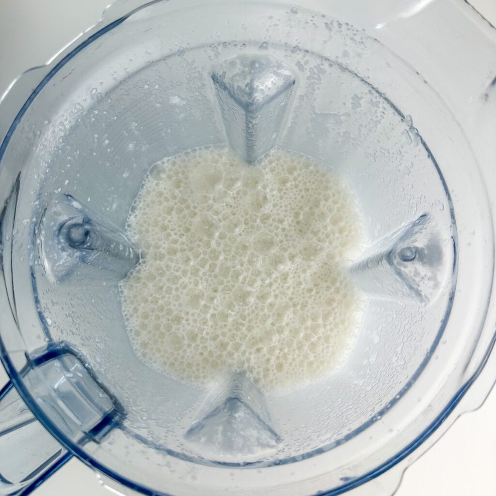 Coconut shake blending in a high-speed blender with fresh coconut water, coconut meat, milk, and ice.