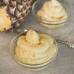 Homemade pineapple Dole Whip being blended, transferred to a piping bag and served in a bowl.